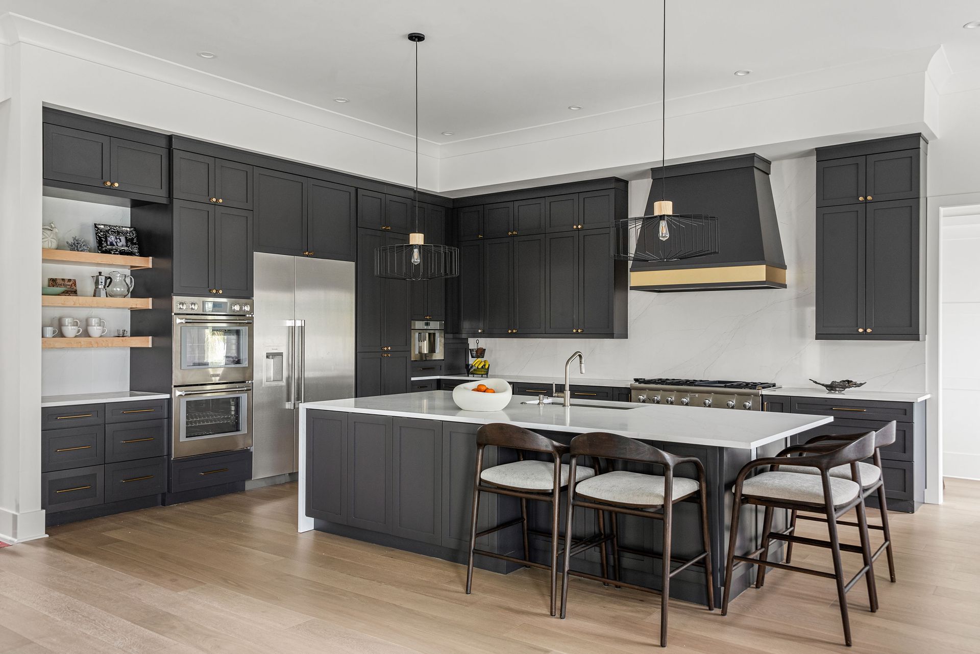 Modern kitchen with dark cabinets, stainless appliances, and a large island with bar stools