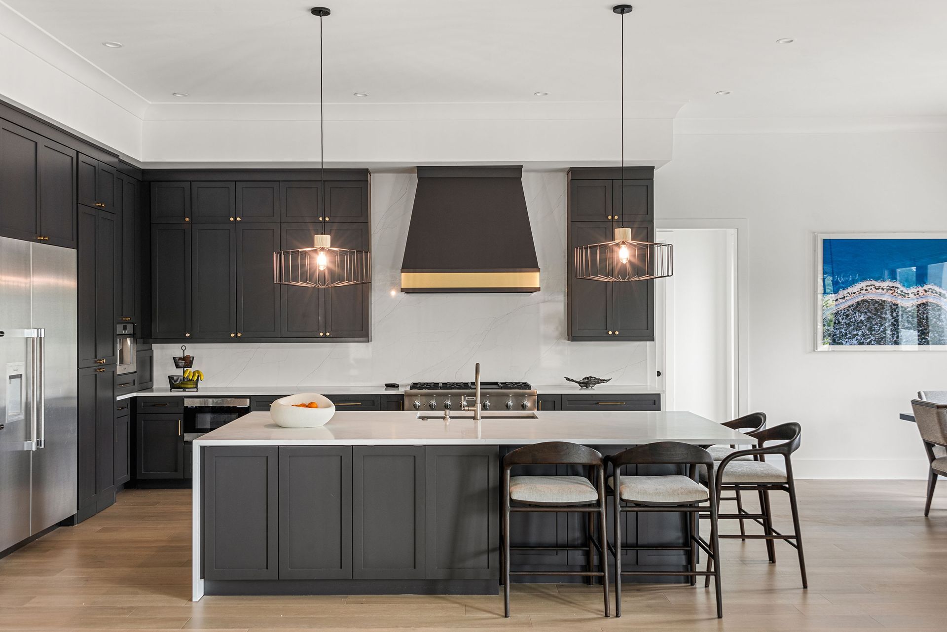 Modern kitchen with dark cabinets, stainless appliances, island seating, and pendant lights