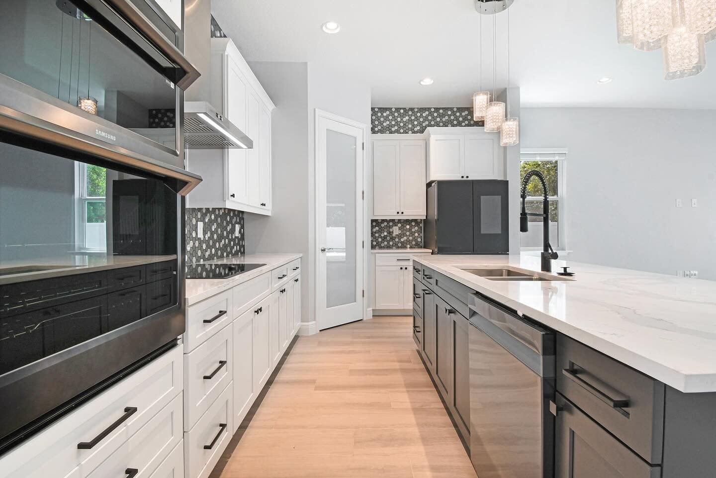 Modern kitchen with white cabinets, dark island, and stainless-steel appliances, viewed from the hallway