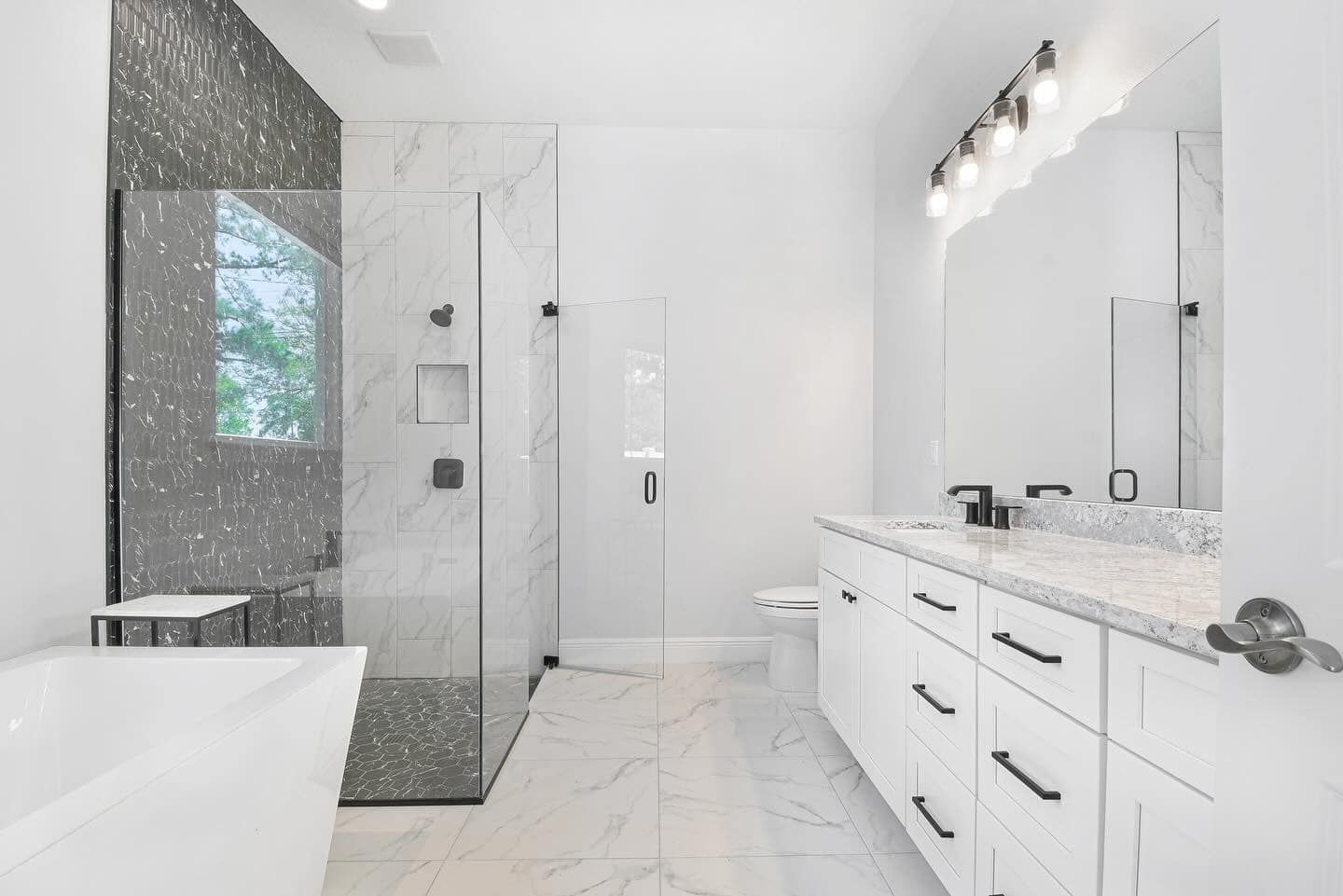 Bright modern white bathroom with double vanity, glass shower, and marble tile floor