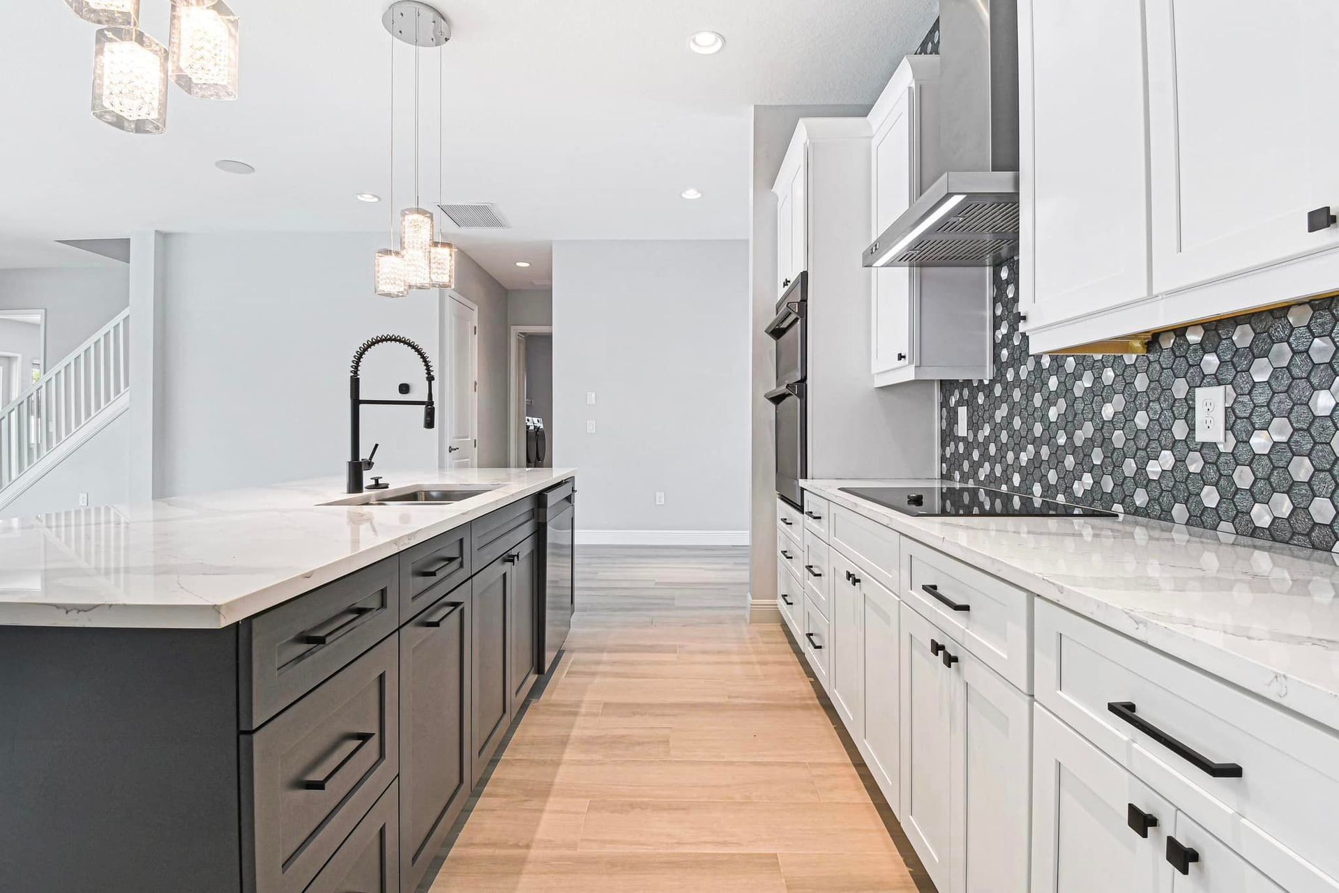 Modern kitchen with white cabinets, dark island, patterned tile backsplash, and wood floors