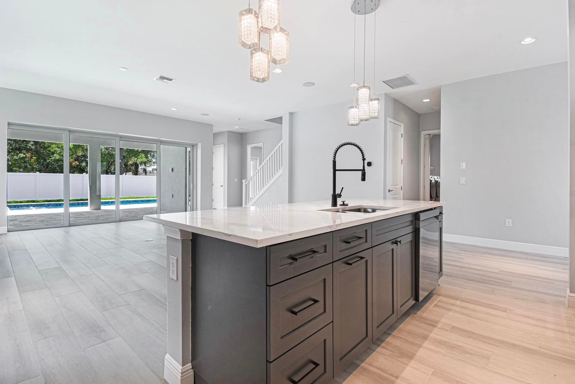 Modern open-concept kitchen with dark island, white cabinets, and large sliding glass doors