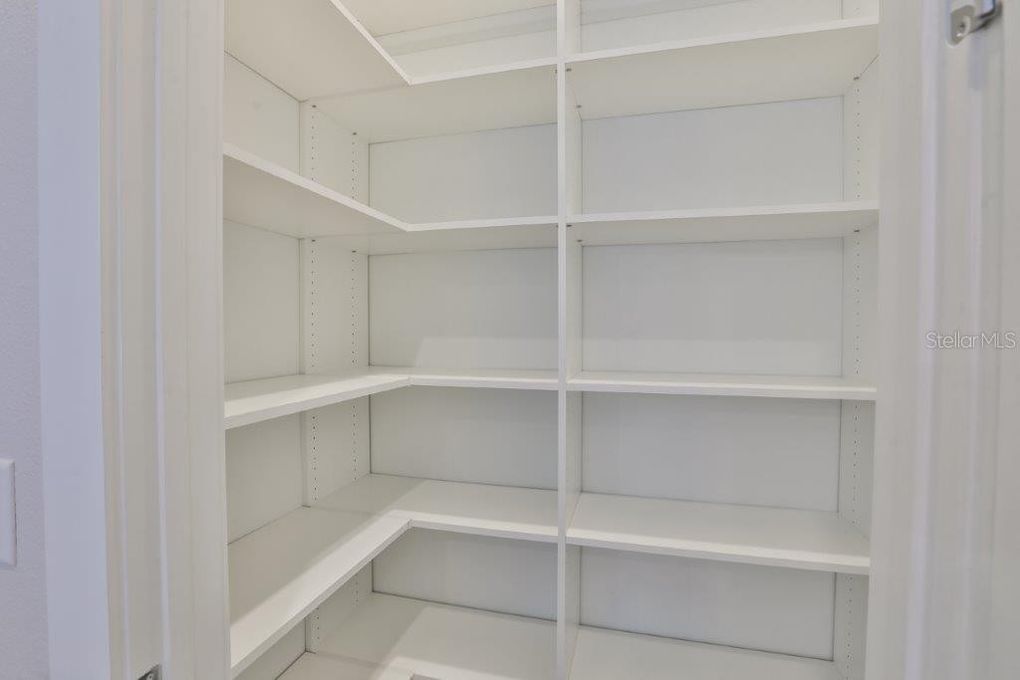 Empty white walk-in closet with built-in shelving and hanging rods