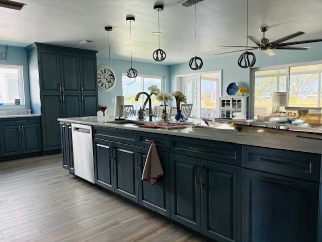 Modern kitchen with dark blue cabinets, large island, pendant lights, and bright windows