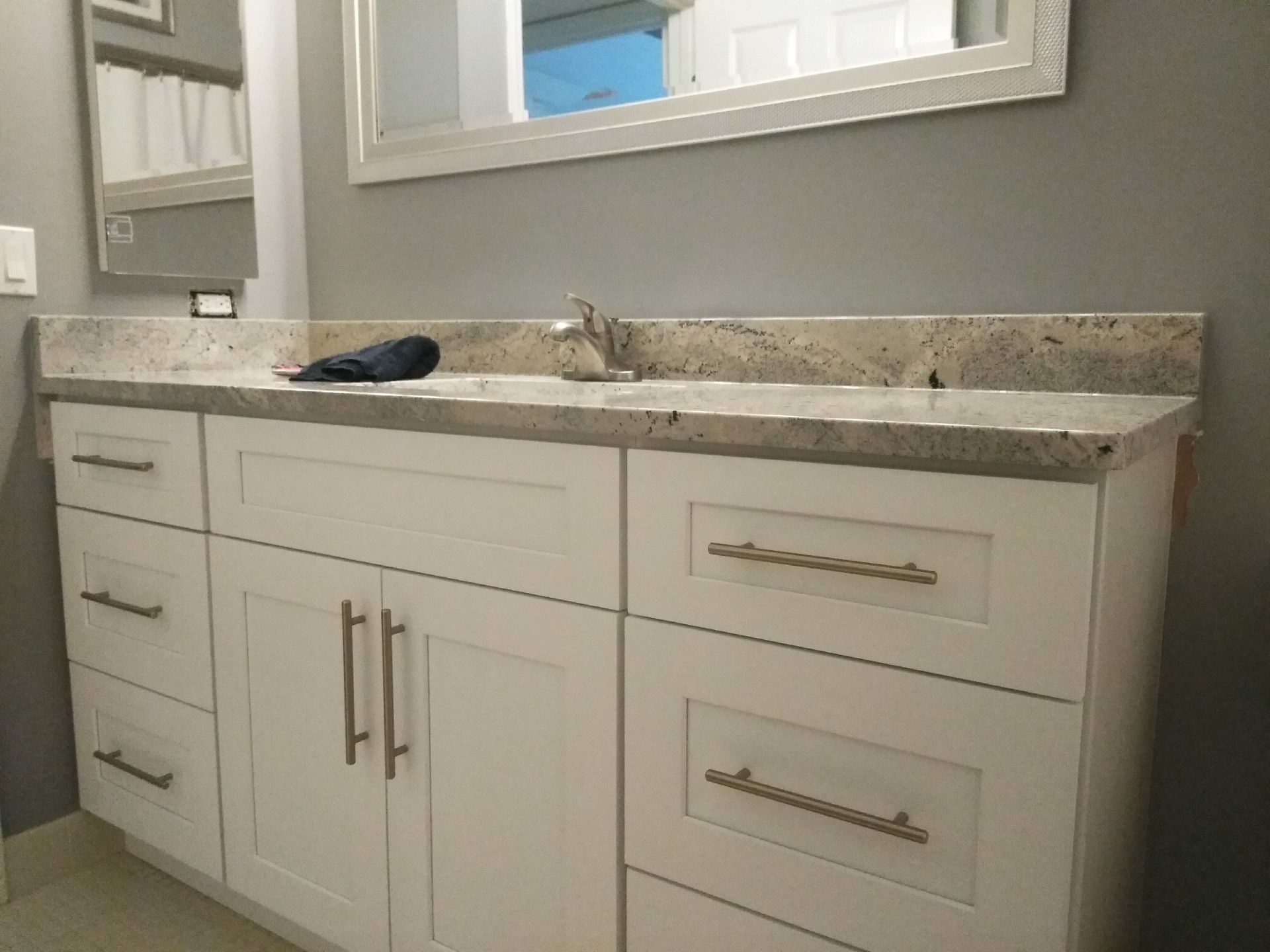 Modern bathroom vanity with double sink, white cabinets, and marble countertop under a wall mirror