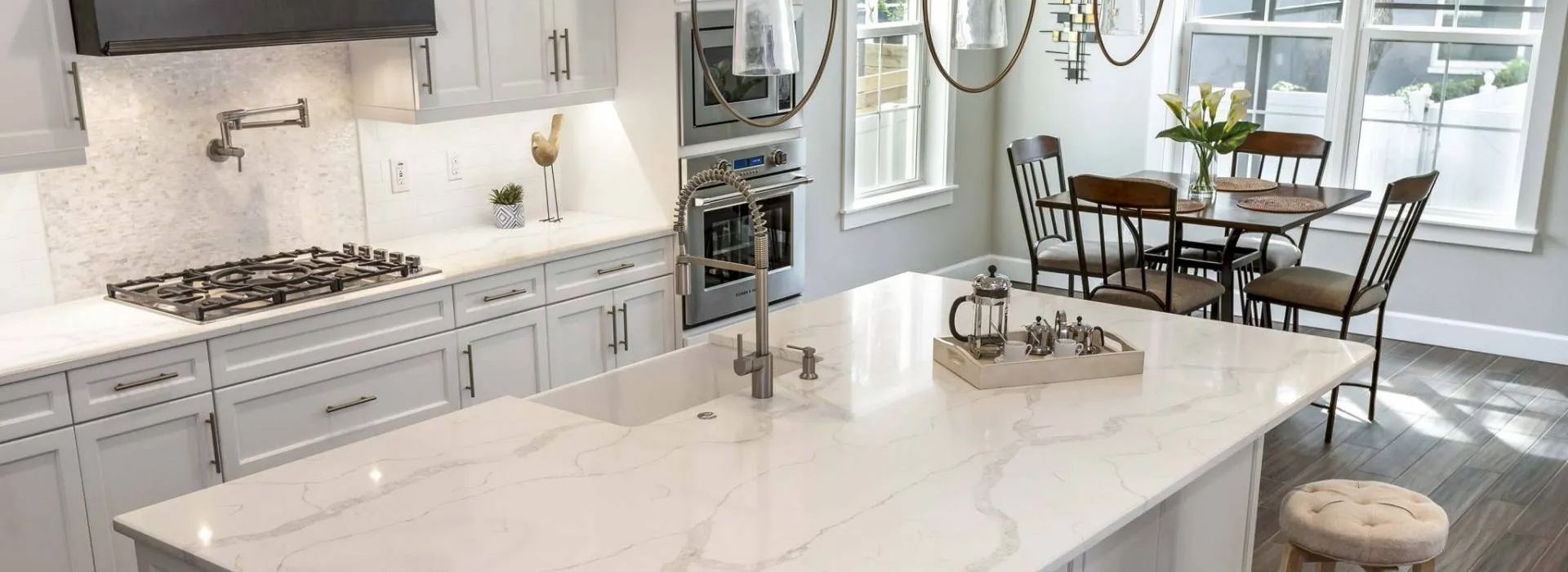 Bright modern kitchen with white marble island, stainless appliances, and adjacent dining area