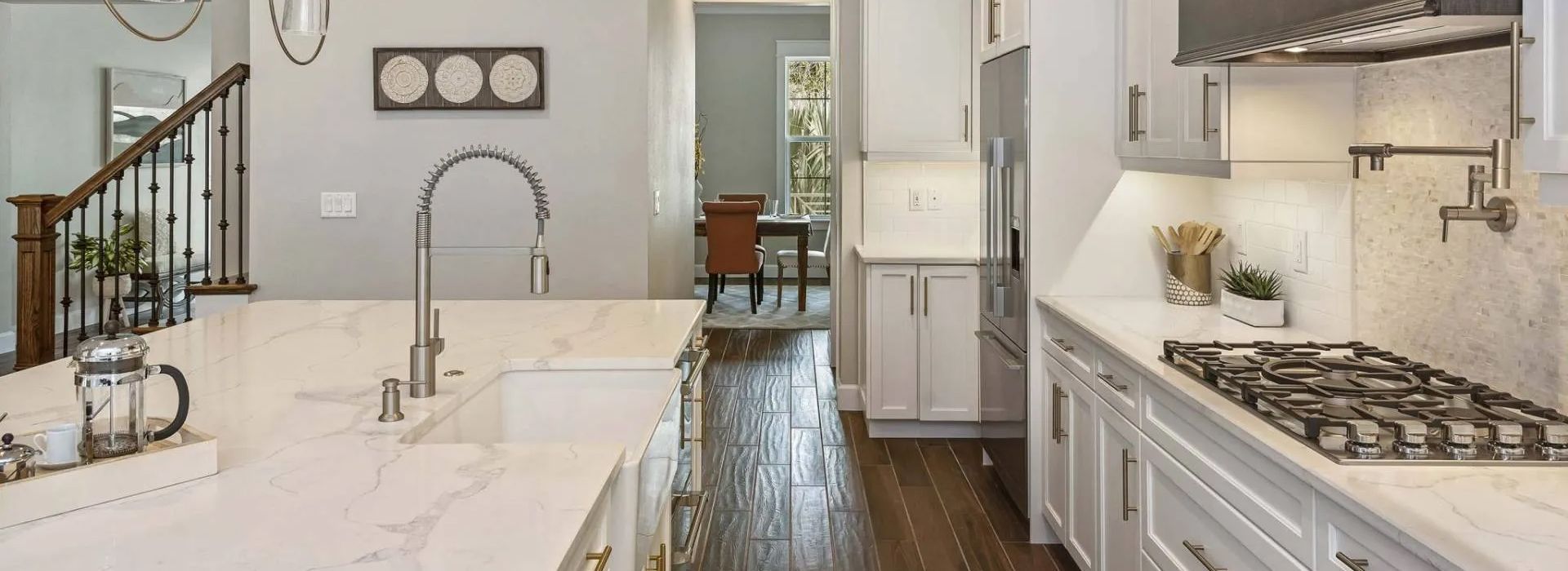 Bright modern kitchen with white cabinets, marble island, stainless sink, and gas cooktop