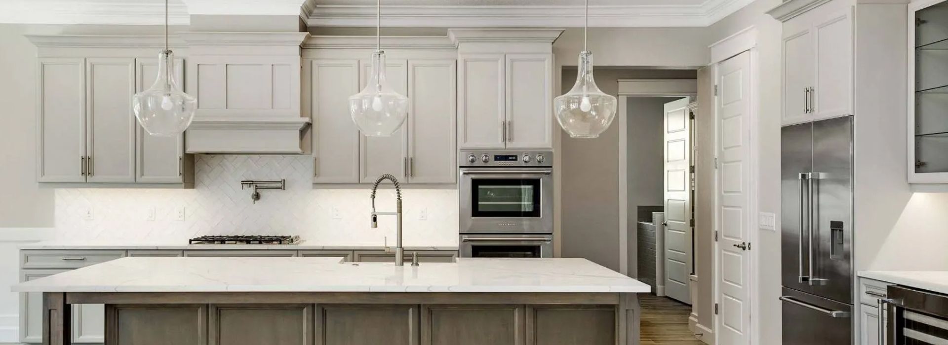 Bright modern kitchen with white cabinets, marble island, and stainless steel appliances