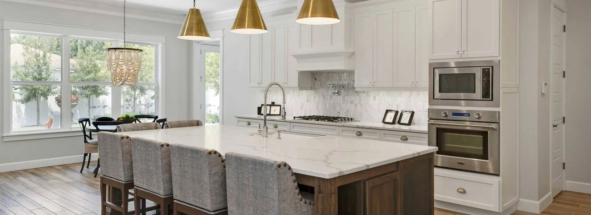 Bright white modern kitchen with large island, pendant lights, and built-in stainless steel ovens