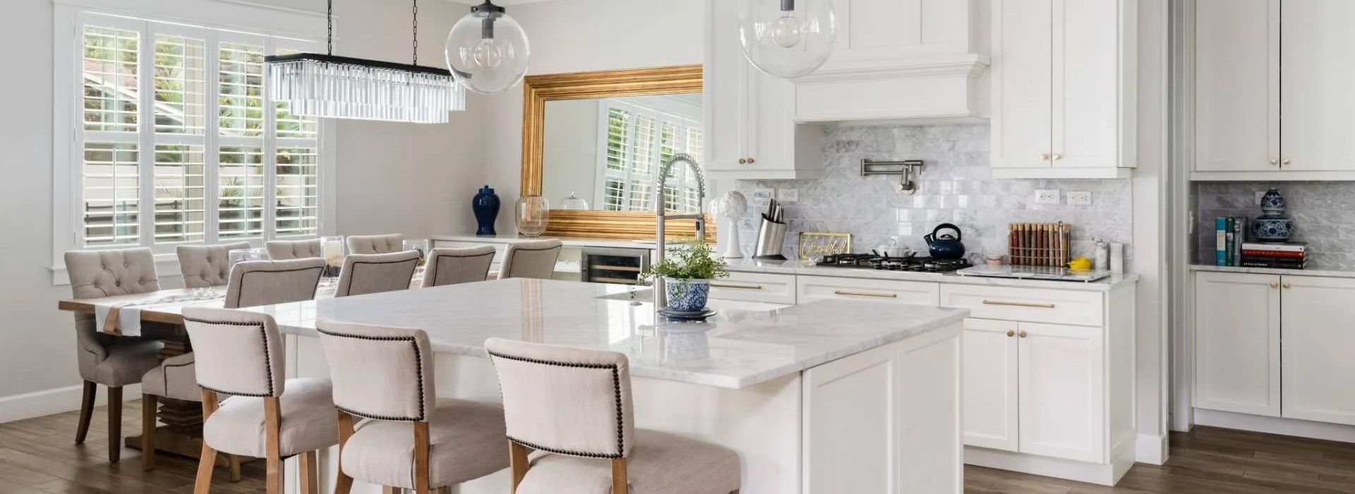 Bright modern white kitchen with island, bar stools, pendant lights, and open dining area