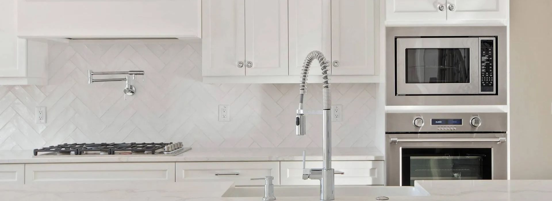 Modern white kitchen with gas stove, sink, and built-in microwave/oven.