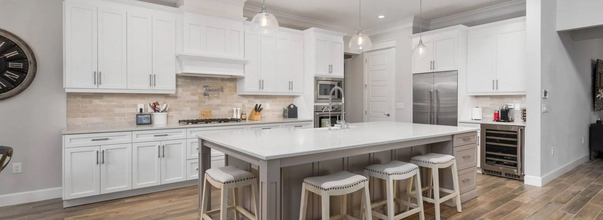 Bright white kitchen with large island, pendant lights, and four stools in a modern open layout