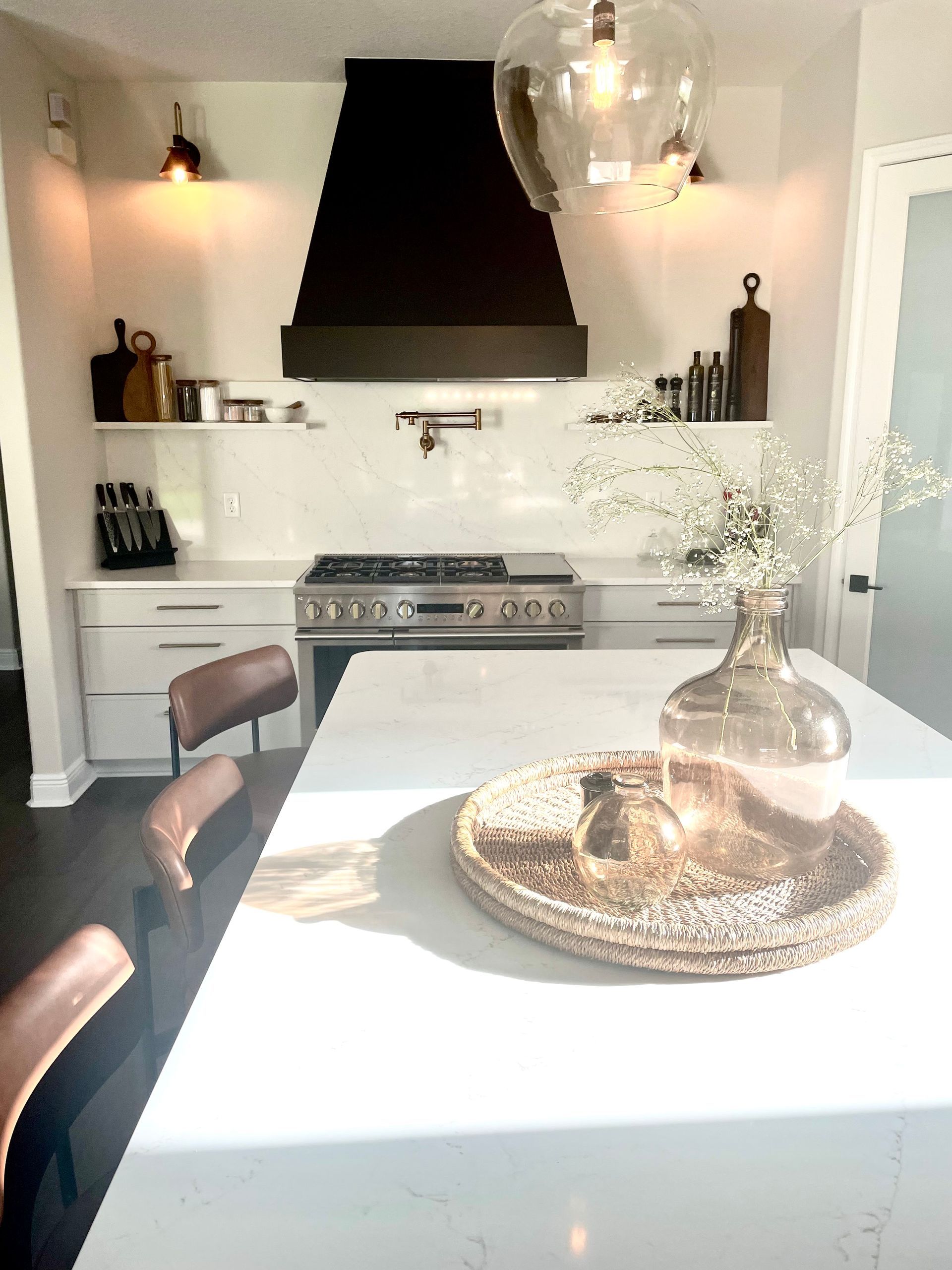 Bright modern kitchen with black range hood, white island, and a tray centerpiece on the countertop.