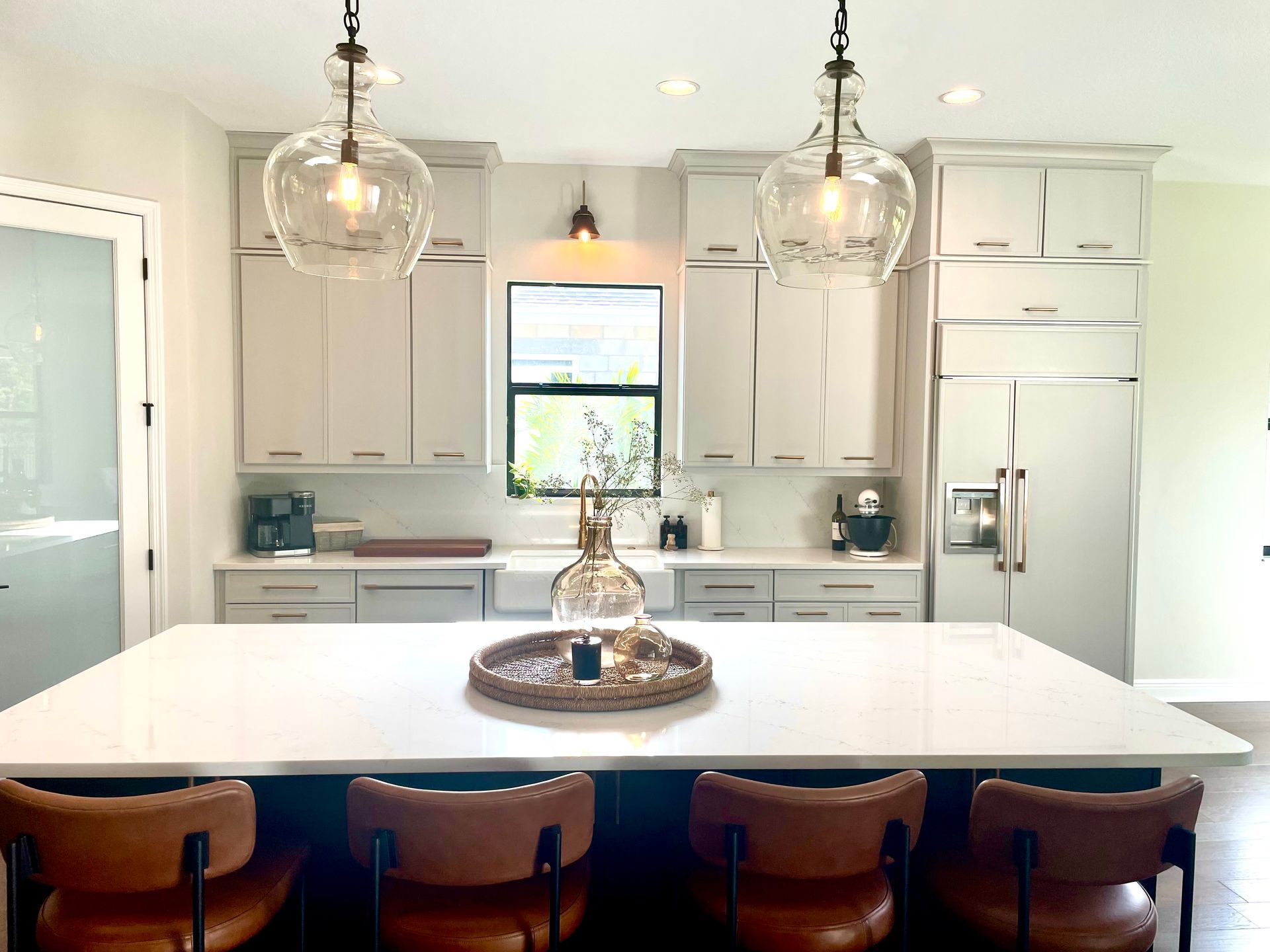 Bright modern kitchen with white cabinets, island, pendant lights, and four wooden stools