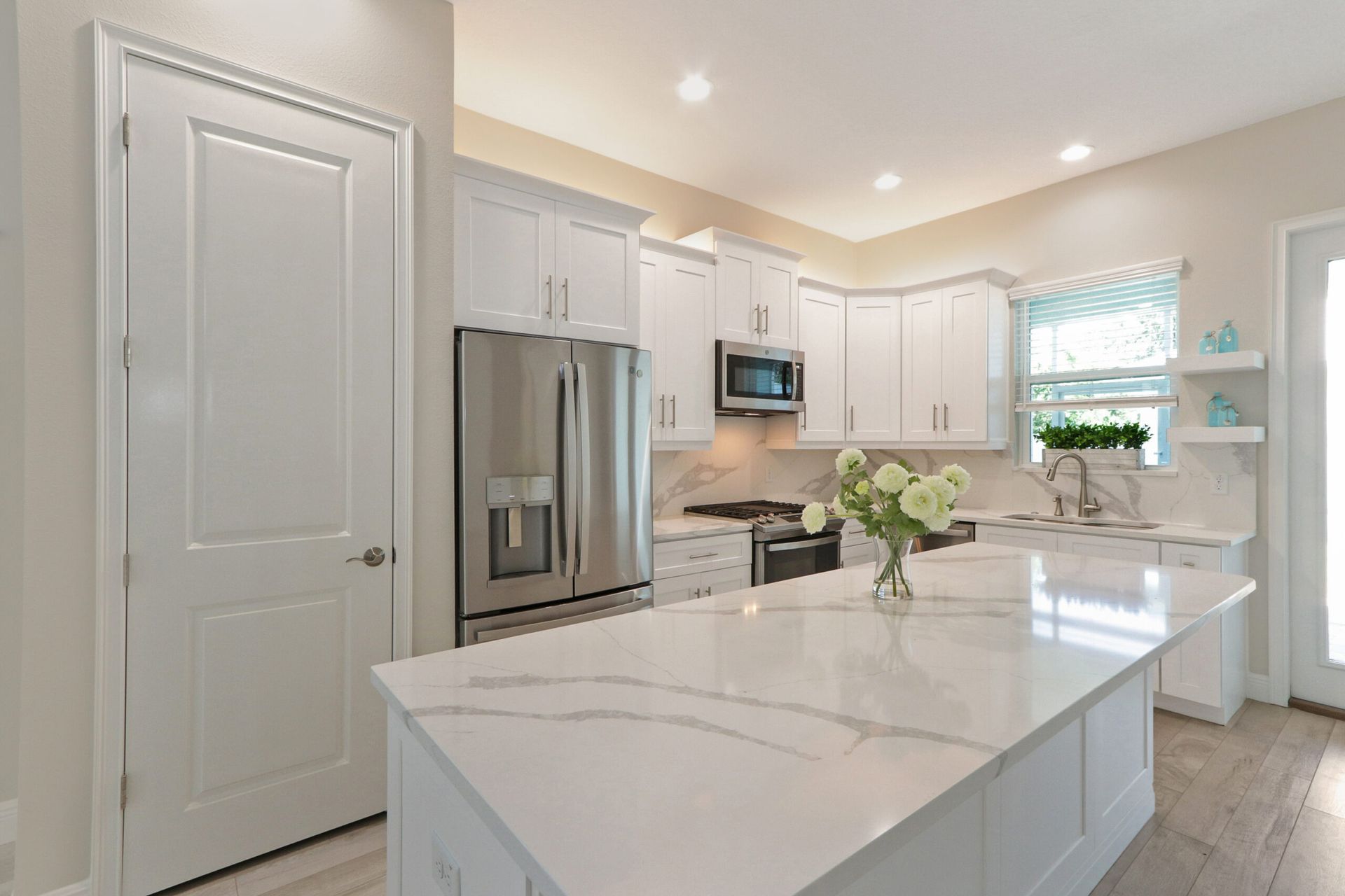 Bright modern white kitchen with stainless steel appliances and a marble island countertop