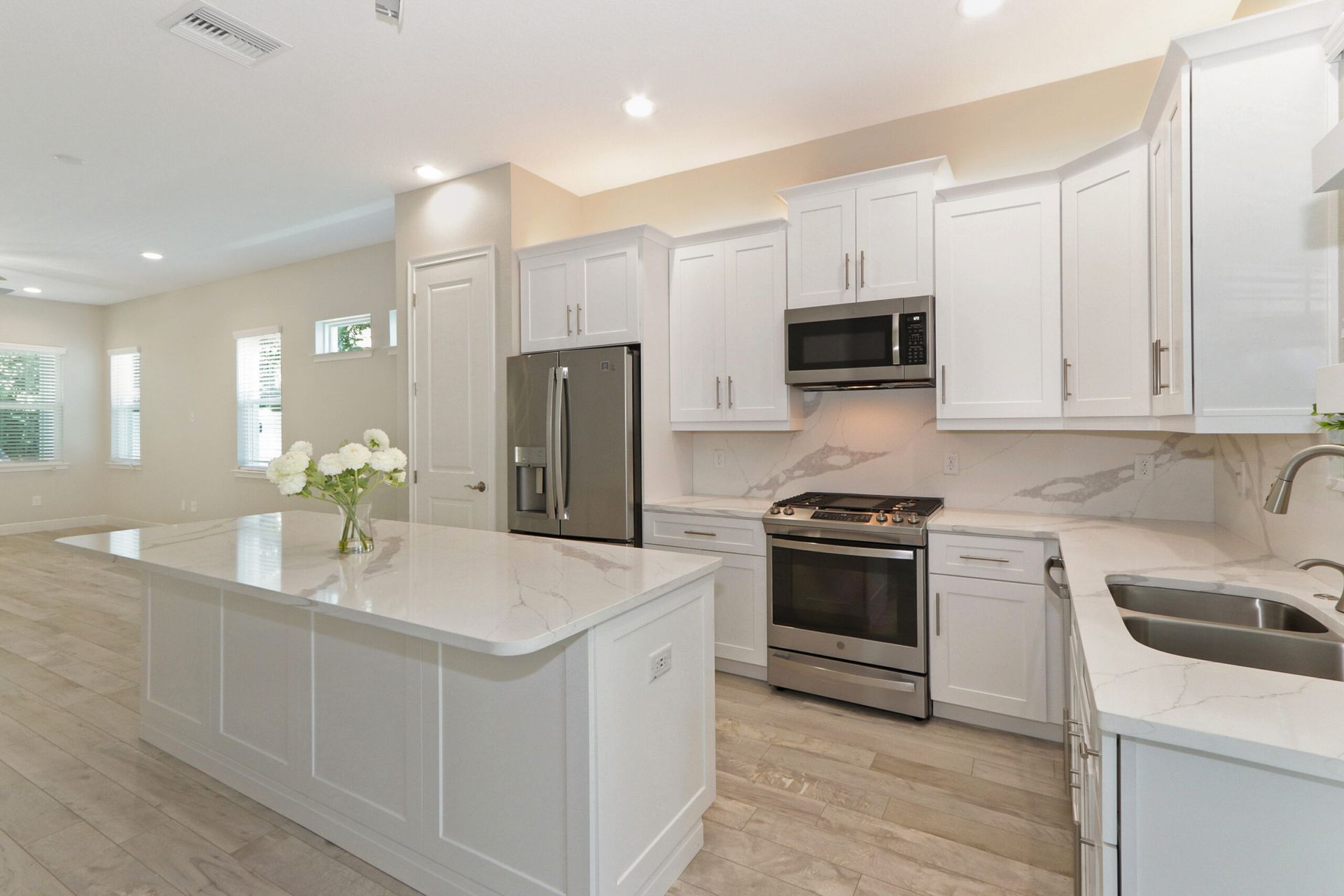 Bright modern kitchen with white cabinets, stainless steel appliances, and a large island