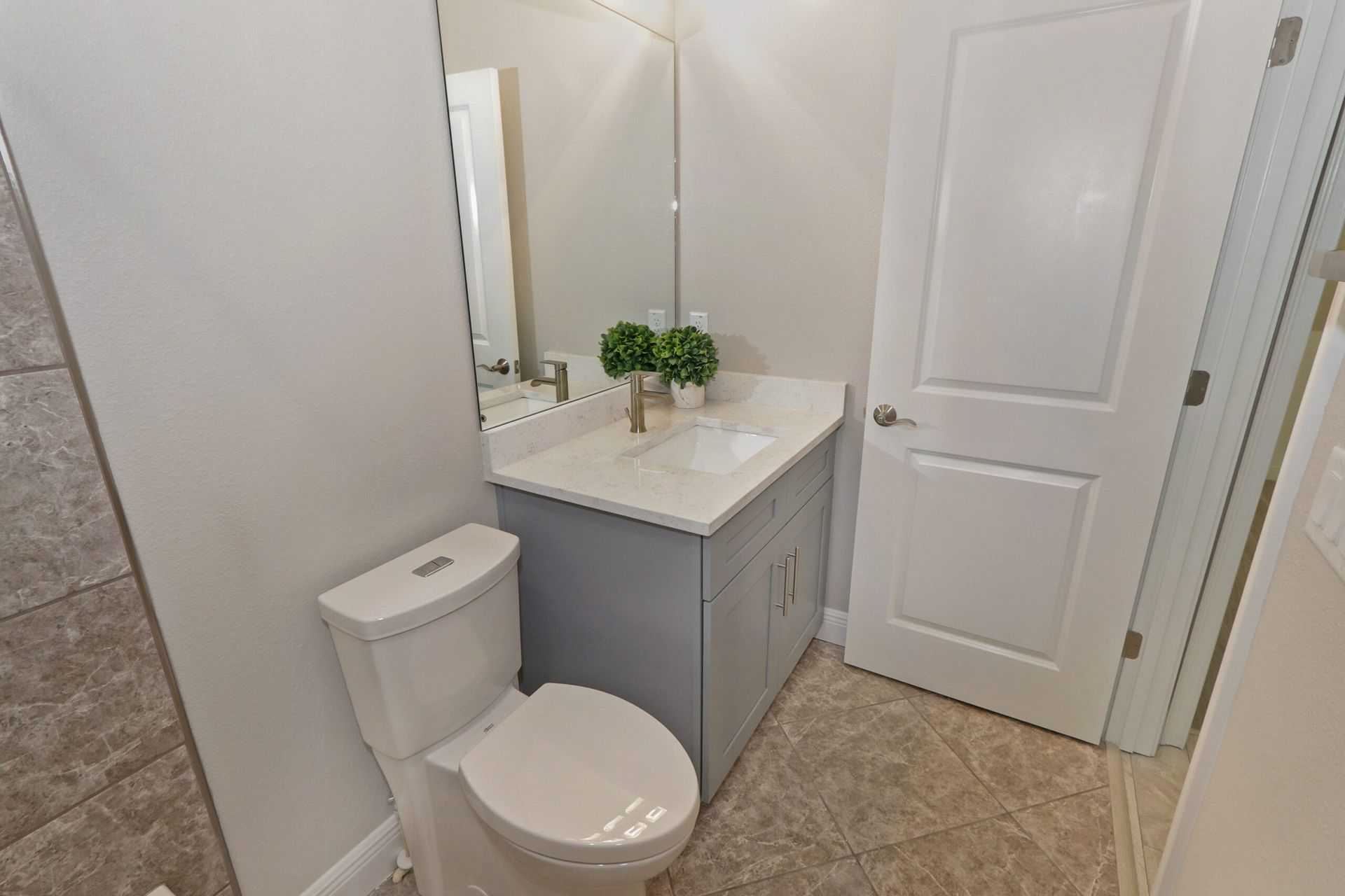 Small bathroom with toilet, vanity sink, mirror, and white door.