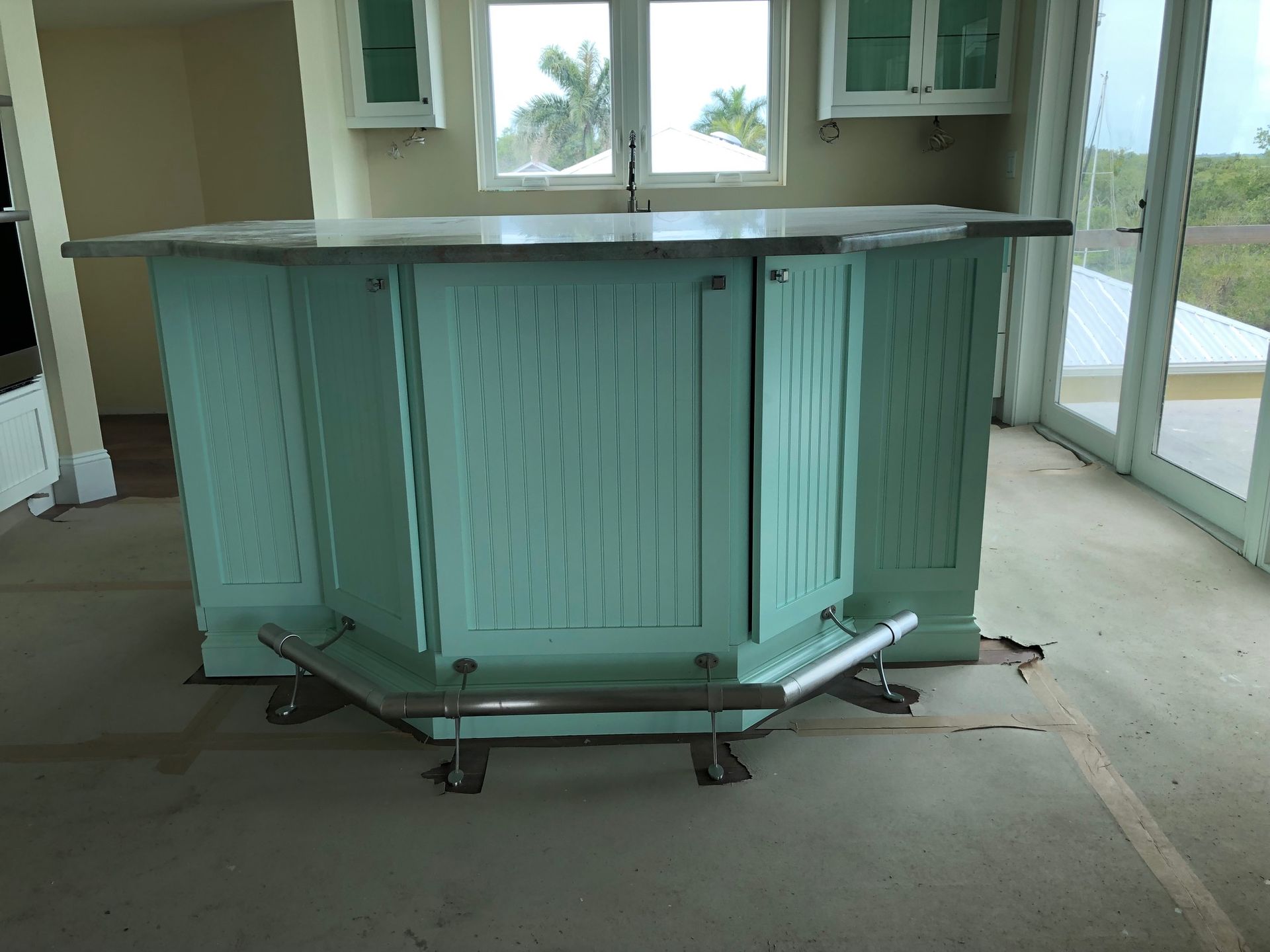 Light blue outdoor bar counter with a dark countertop on a patio floor