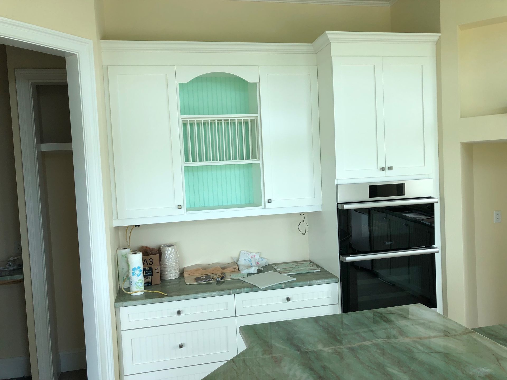 White kitchen with cabinets, stove, countertop items, and a green bed in the foreground