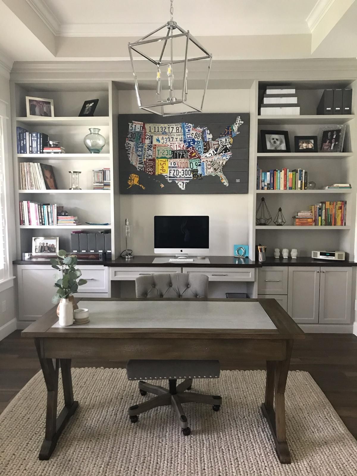 Home office with built-in shelves, desk, computer, and wall art in a bright room
