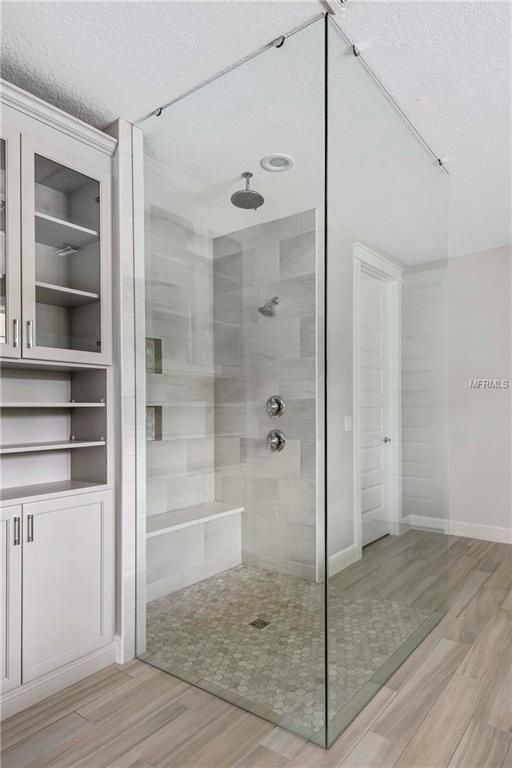 Modern bathroom with a glass-enclosed shower, gray tile, and light wood flooring
