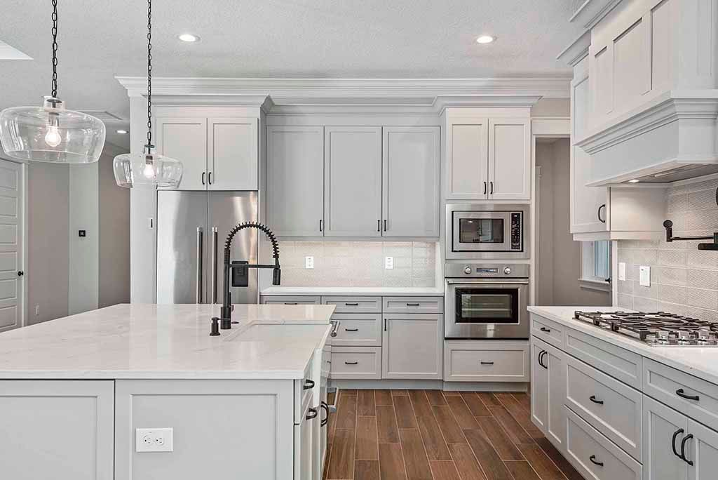 Bright white modern kitchen with island, stainless appliances, gray cabinets, and hardwood floor