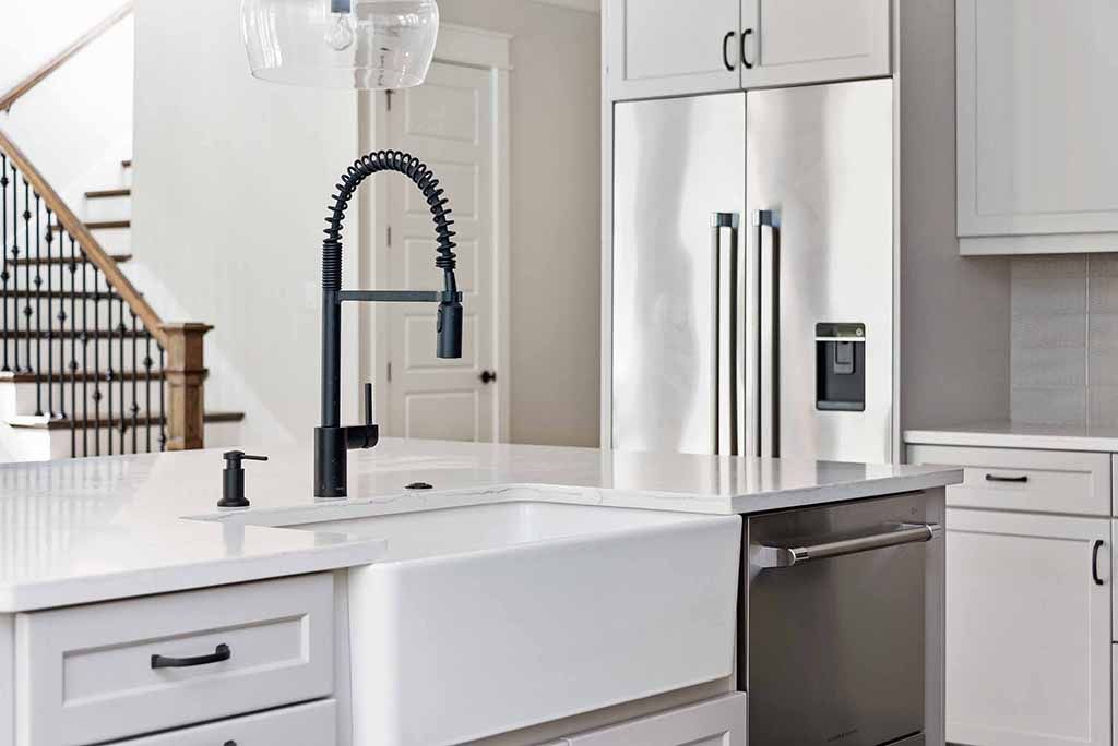 Modern white kitchen with stainless steel appliances and a farmhouse sink