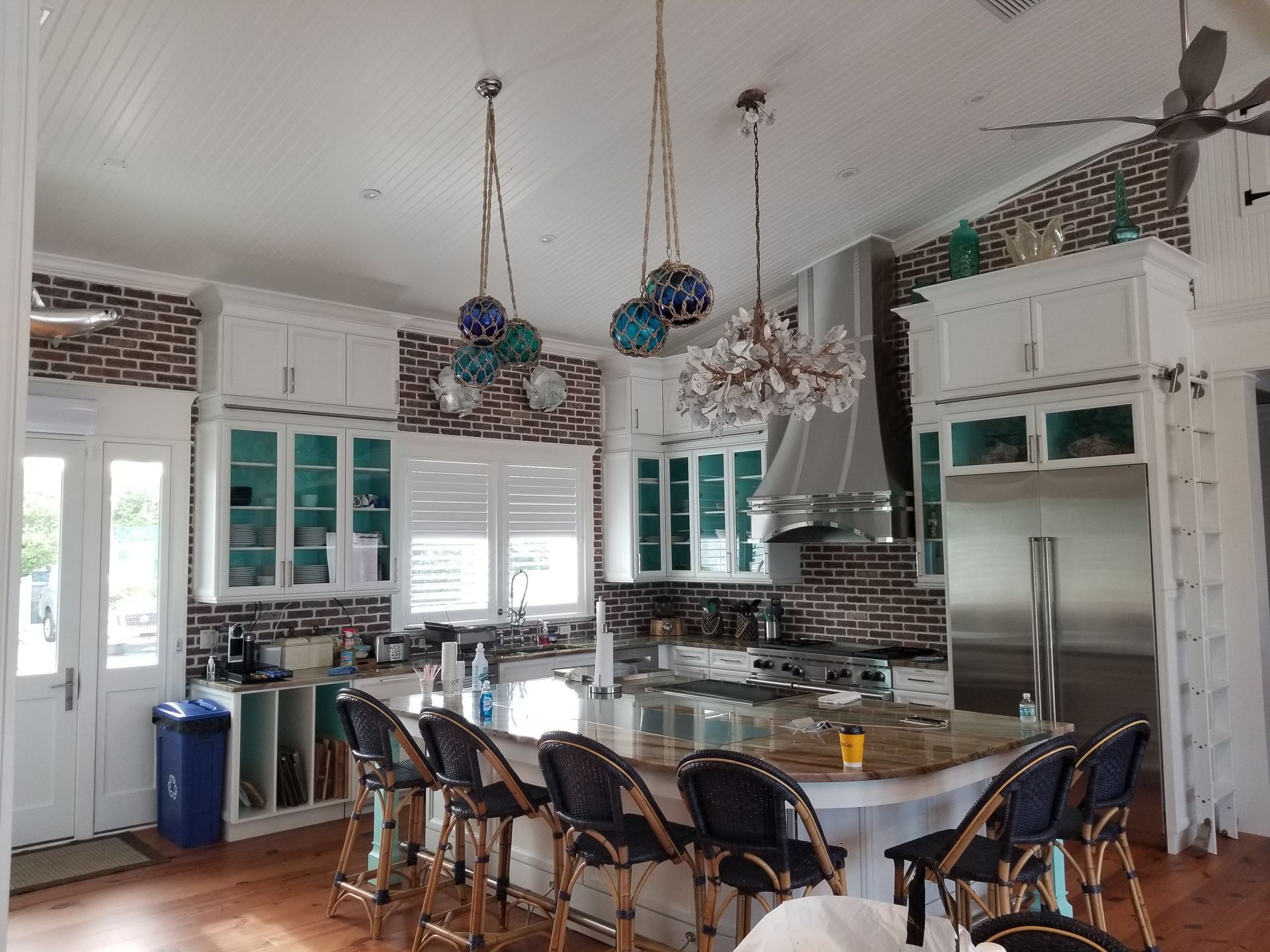 Bright modern kitchen with white cabinets, large island, hanging pendant lights, and barstools
