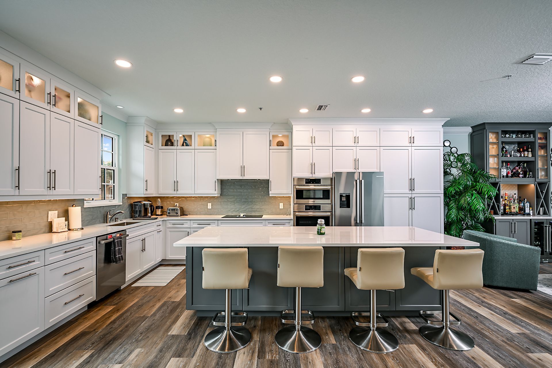 Modern white kitchen with island, green bar stools, and stainless steel appliances