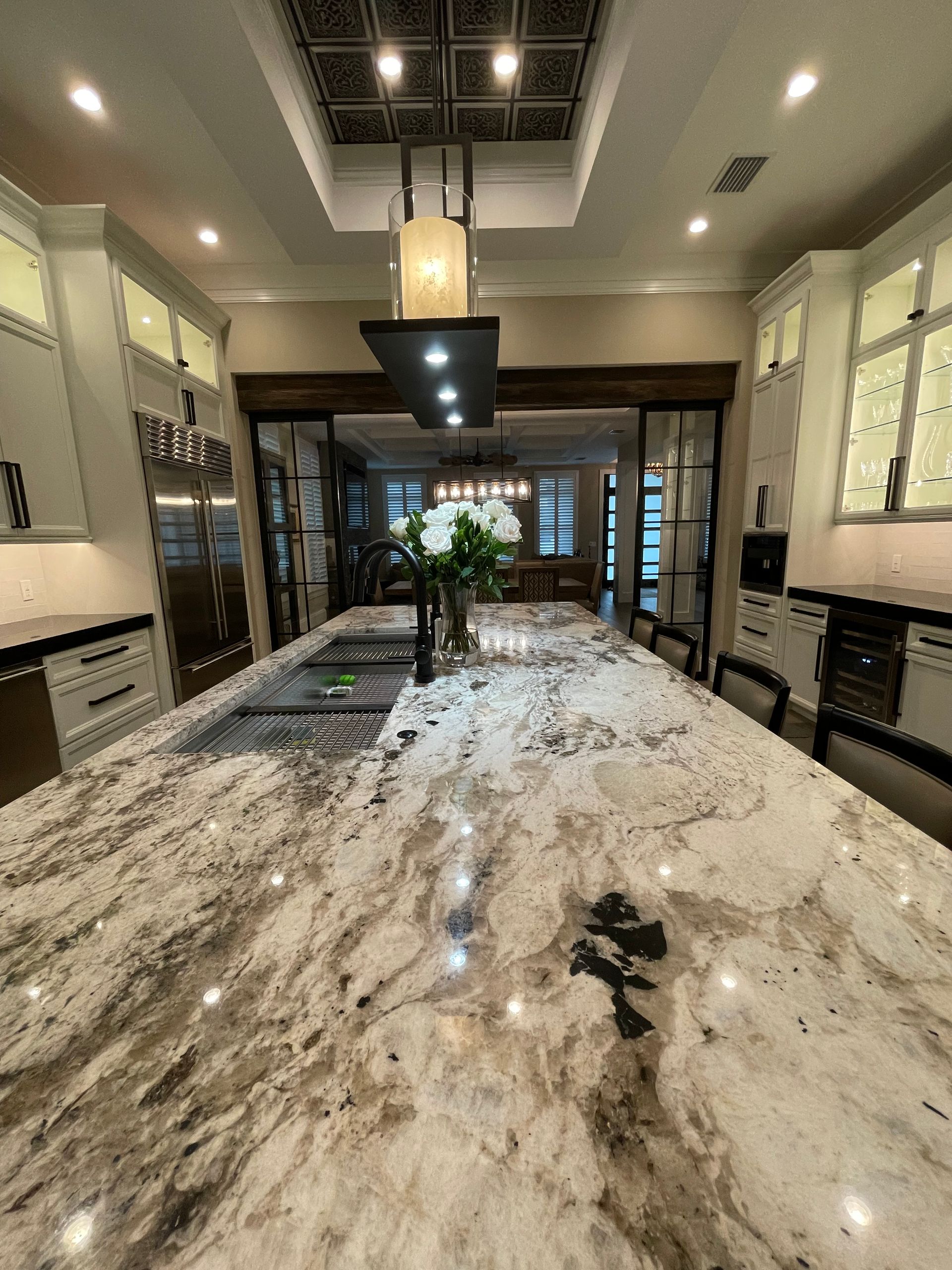 Luxury kitchen with a large marble island, pendant lights, and built-in cabinets