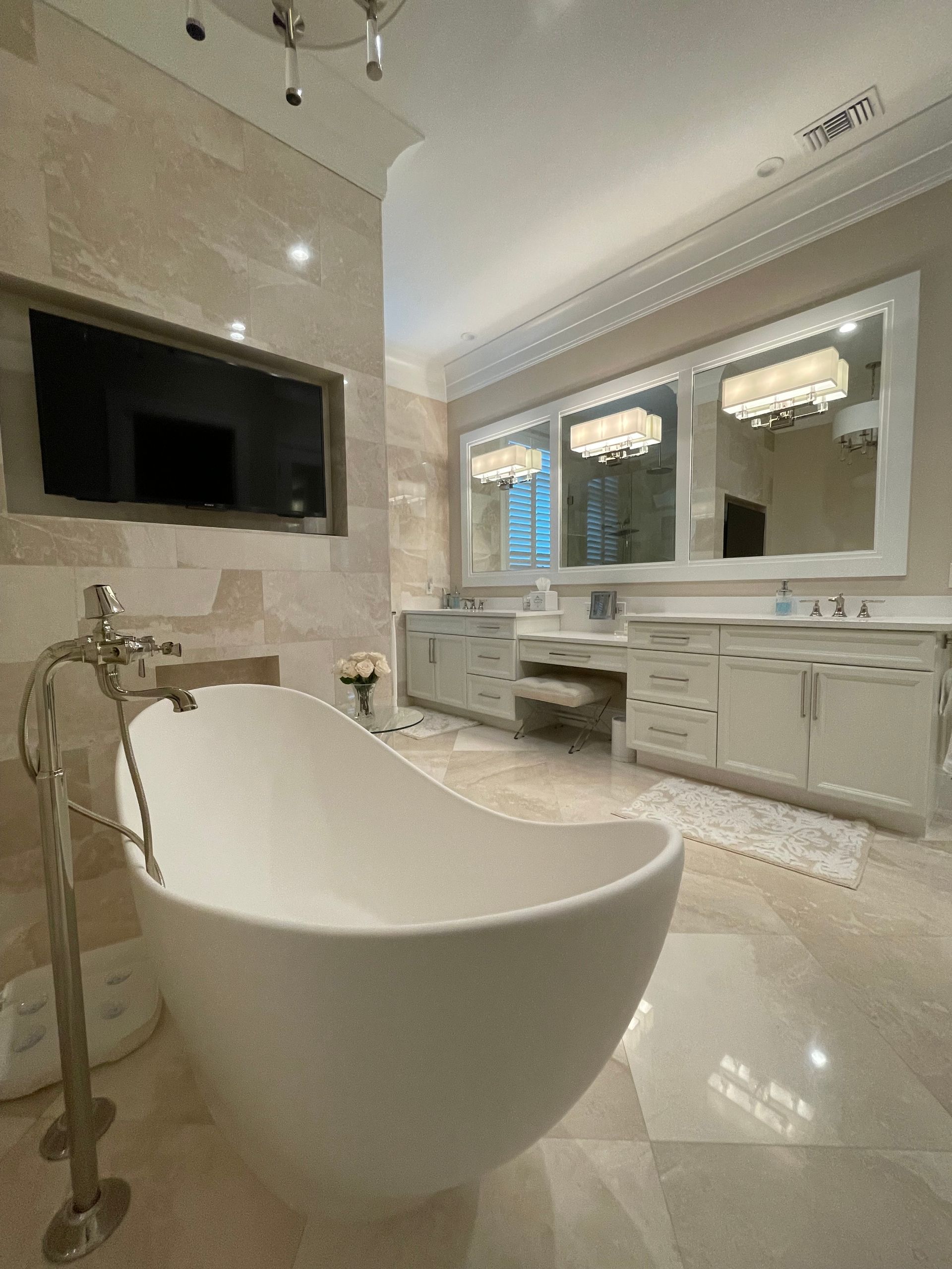 Luxury bathroom with freestanding white tub, marble tile, and double vanity under a large window