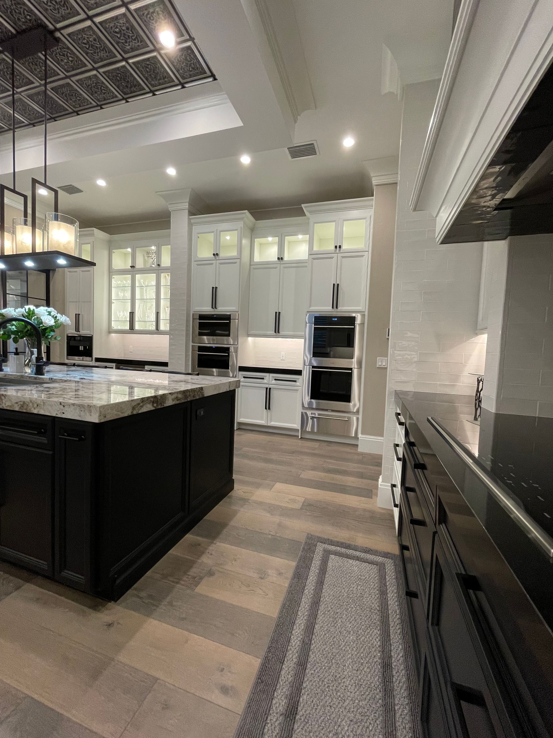 Modern white kitchen with a large island, built-in appliances, and a long runner rug