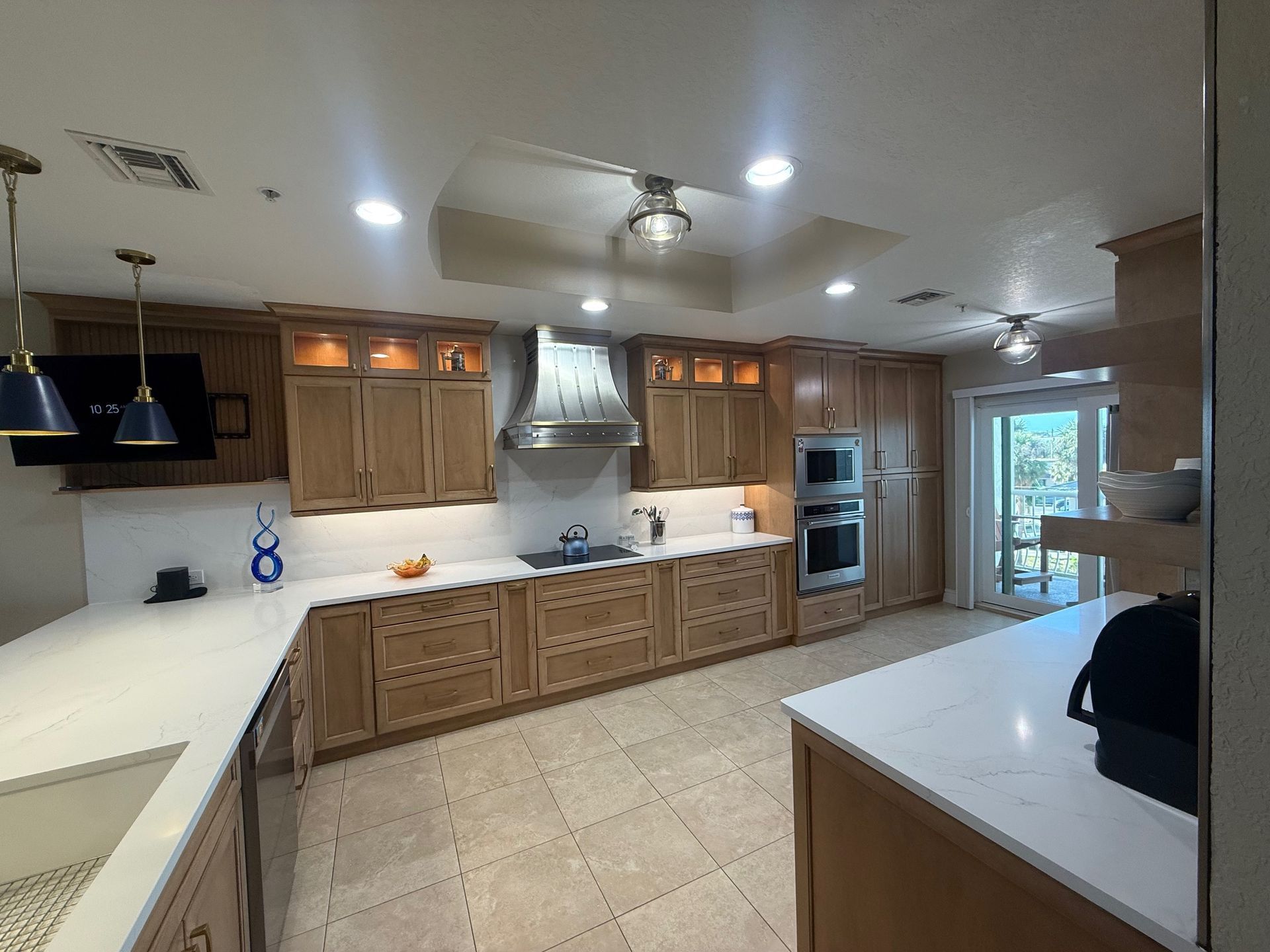 Bright modern kitchen with wood cabinets, white counters, tiled floor, and stainless appliances