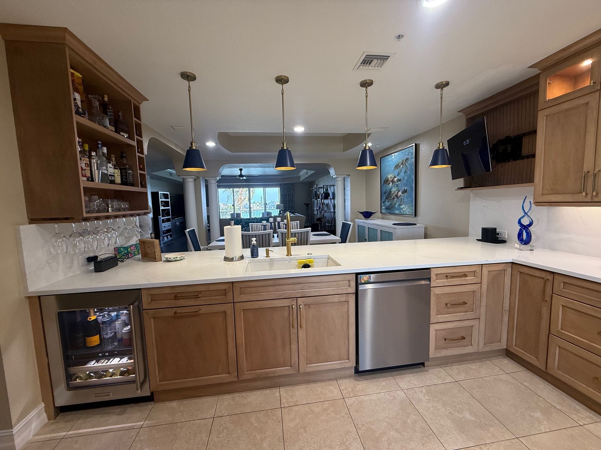 Modern kitchen with wood cabinets, white countertops, island seating, and stainless steel appliances.