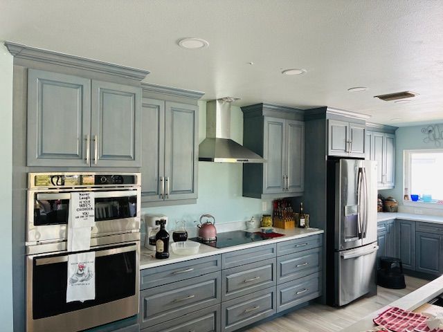 Modern kitchen with blue-gray cabinets, stainless appliances, and a countertop island