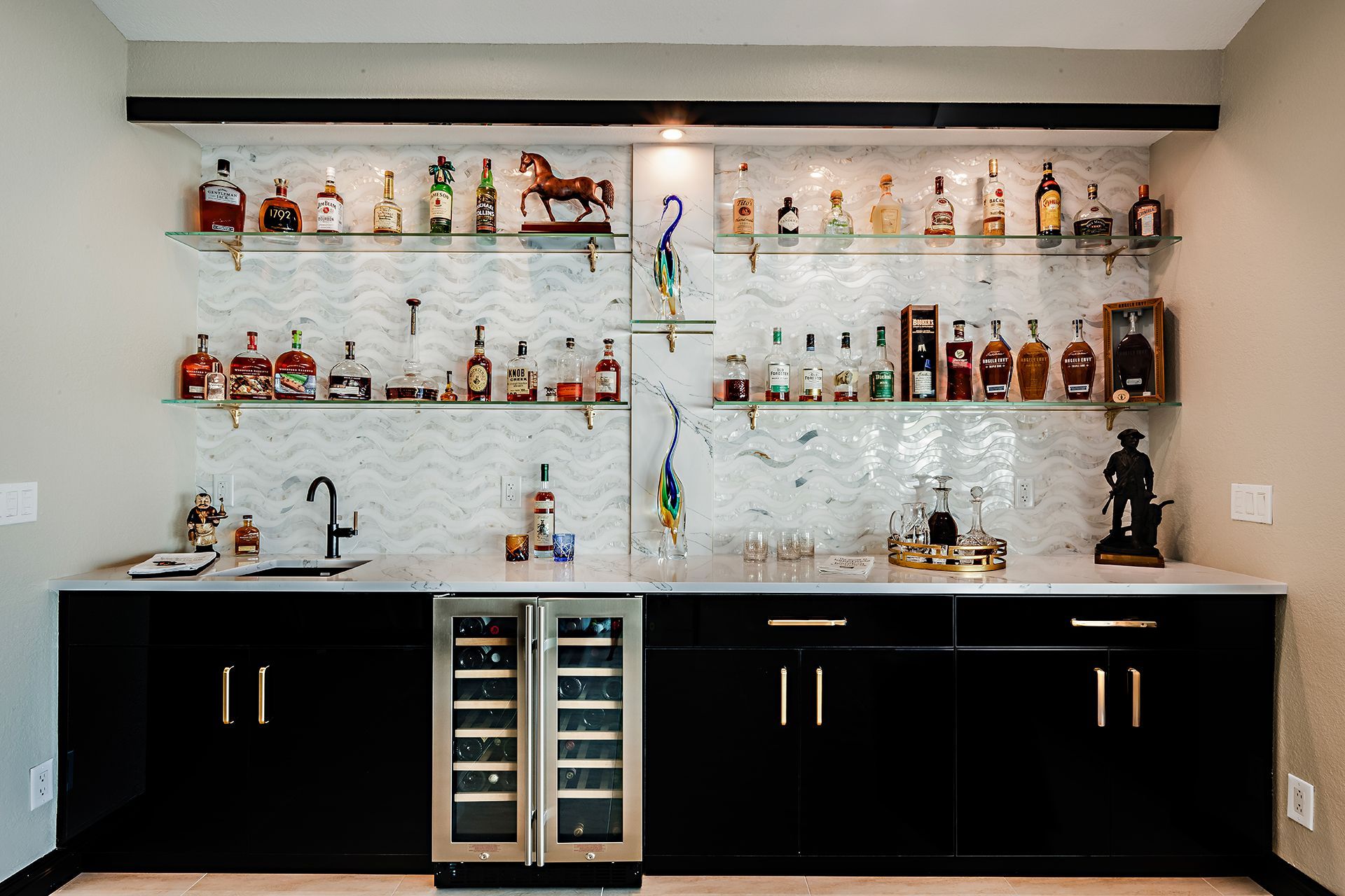 Home bar with black cabinets, mirrored backsplash, and shelves of liquor bottles and glassware