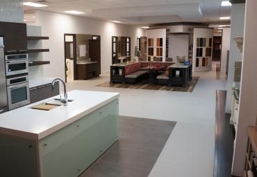 Modern kitchen showroom with white counters, wood cabinets, and a central seating display