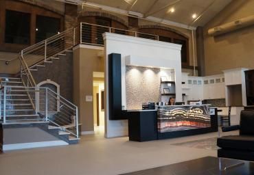 Modern lobby with curved staircase, mezzanine, and reception desk under warm lighting