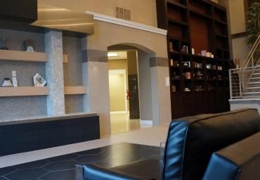 Modern living room with black leather sofas, built-in shelves, and an arched doorway