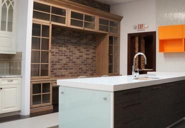 Modern kitchen with white cabinets, dark island, stainless sink, and built-in shelving alcove.