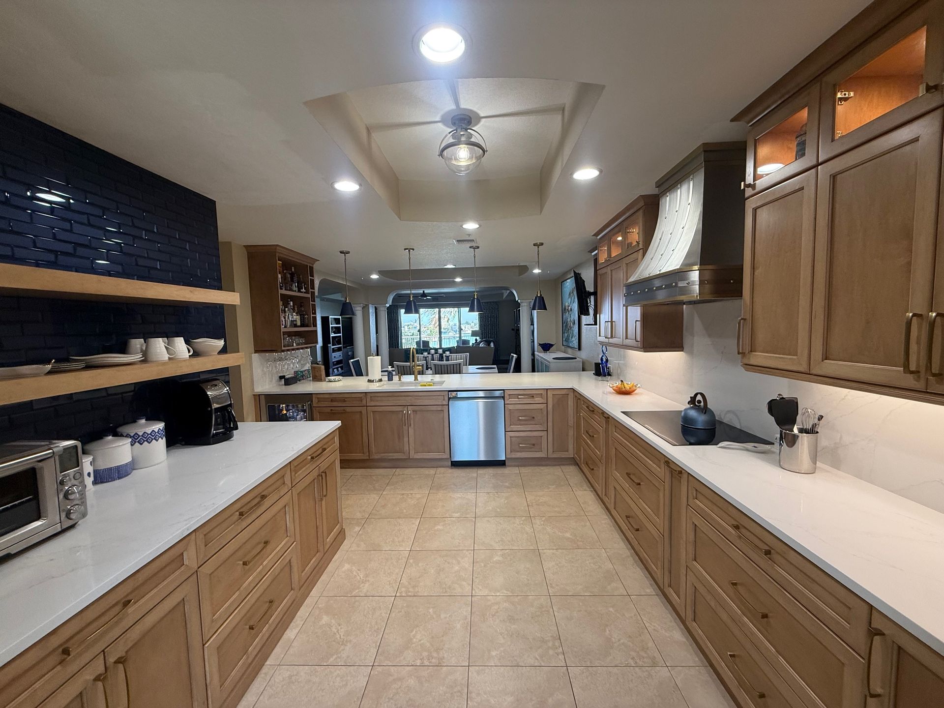 Bright, spacious kitchen with wood cabinets, white countertops, tiled floor, and a central island ceiling fan.