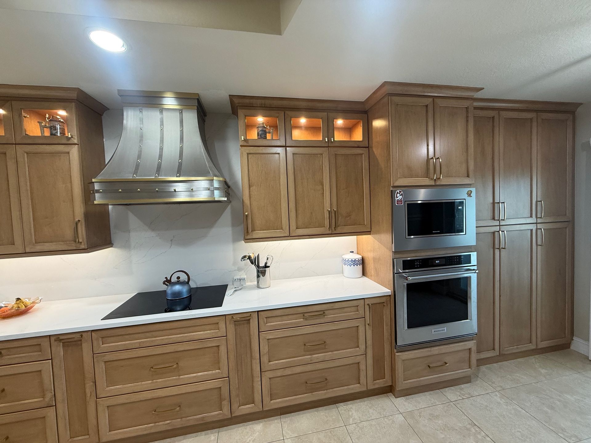 Modern kitchen with wood cabinets, stainless steel appliances, and a central stove under a range hood