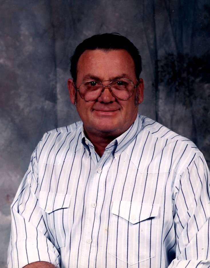 Man in glasses and white striped shirt posing against a gray studio backdrop