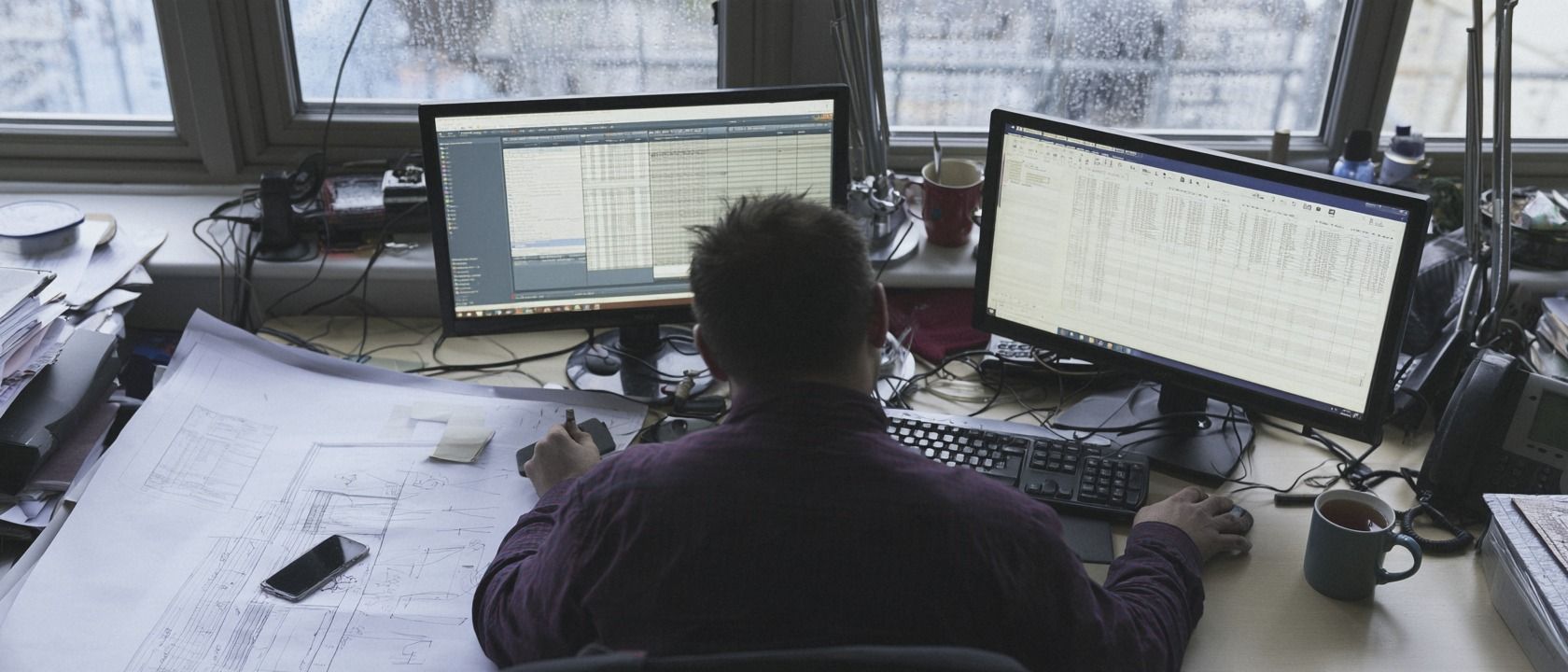 Quantity surveyor reviewing a cost report at a desk in a busy office