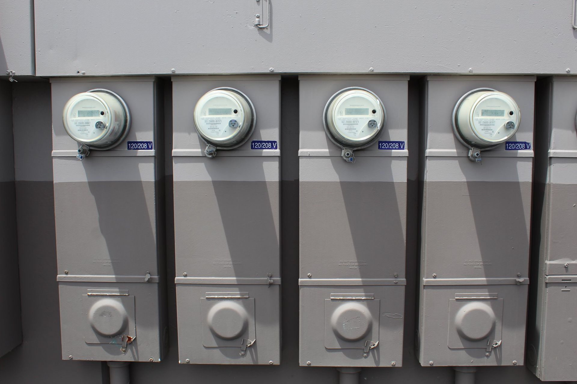 A row of electrical meters are lined up on a wall.