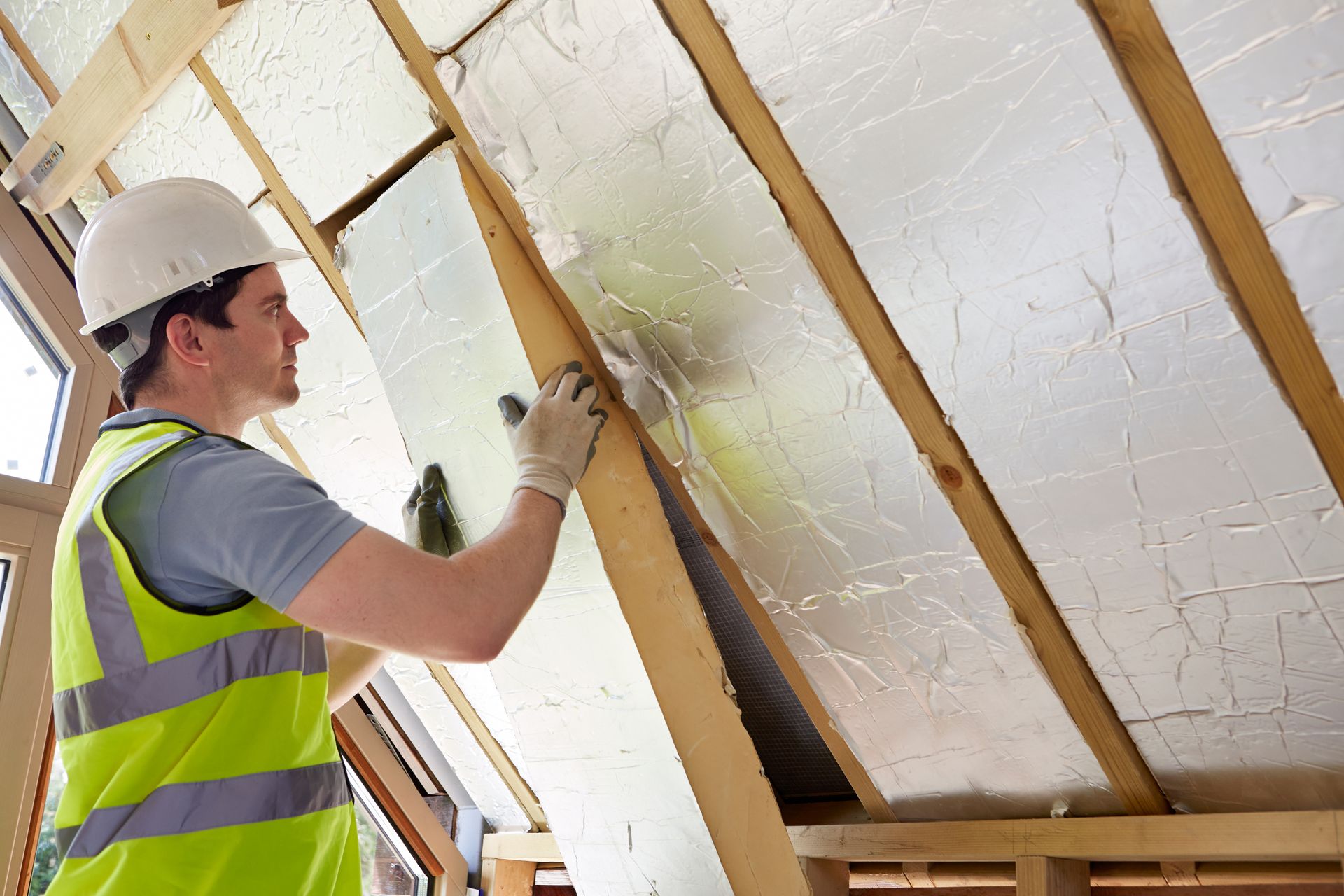 A man is installing insulation on the roof of a building.