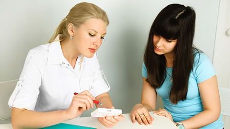 Two women are sitting at a table talking to each other.