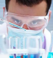 A man wearing a mask and goggles is using a pipette in a laboratory.