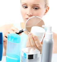 A woman is looking at herself in a mirror surrounded by bottles of cosmetics.