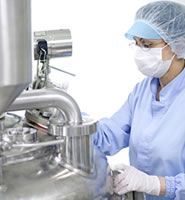 A woman wearing a mask and gloves is working on a machine.